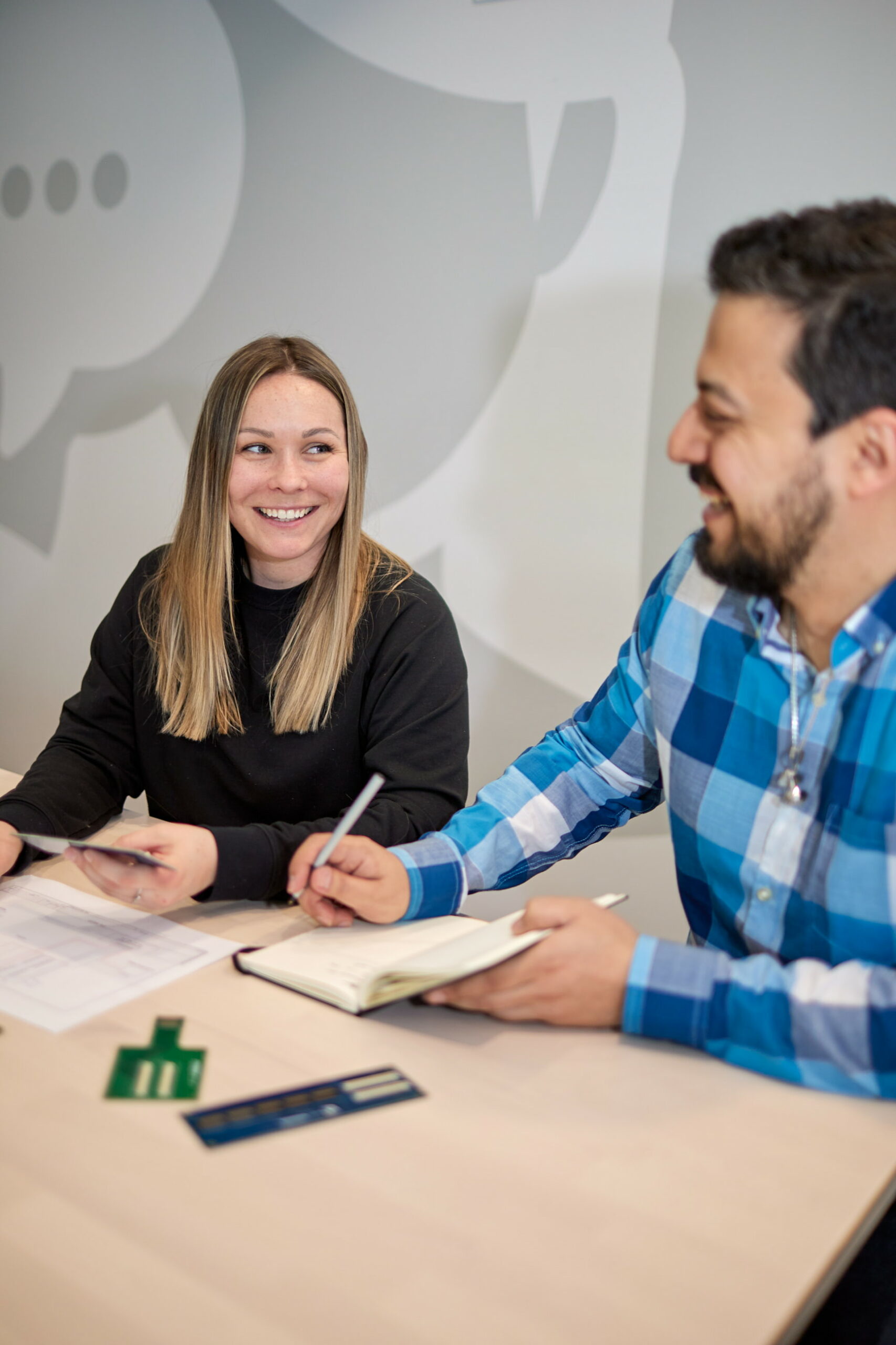 team members sitting at a table discussing notes and laughing together