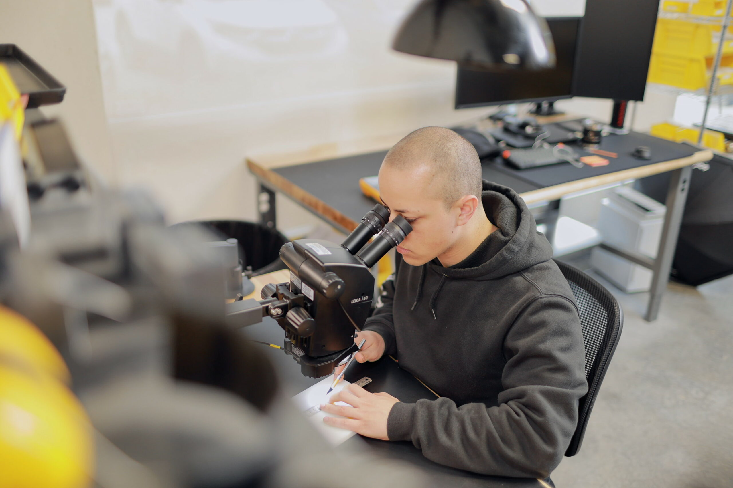 team member looking through a microscope cutting material with a exacto knife and ruler
